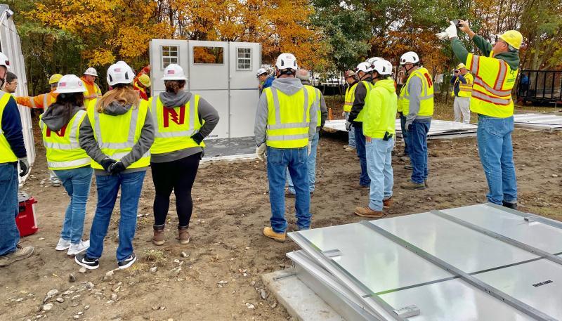 On. Oct. 18, volunteers receive instructions on how to assemble the shelters. They were able to erect 29 of the 40 units that day. MARK CHURA PHOTO